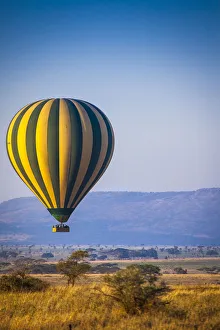 A hot-air balloon slowly traverses over the Serengeti plain