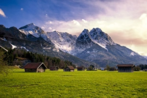 Images Dated 24th April 2012: Huts in field at base of Bavarian Alps with snow at sunset