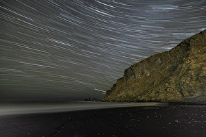 Dark Prints: Iceland, Vik. Myrdal. Star trails above Reynisfjara black sand beach at night