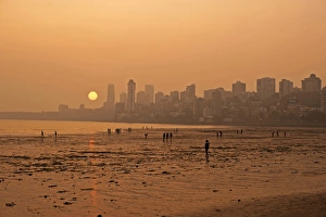 India, Maharashtra, Mumbai, Chowpatty beach, sunset with red sun coming down under India, Maharashtra, Mumbai, Chowpatty beach, sunset with red sun coming down under