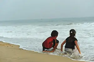Family Prints: India, Odisha, Puri, two girl friends having fun with the waves of the ocean