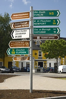 Ireland, County Mayo, Westport. One post holds distance and directional signs in English and Gaelic
