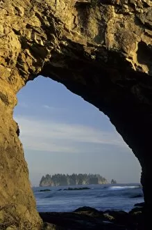 Island viewed through arch in sea stack, Rialto Beach, Olympic National Park, Washington
