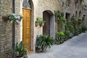 Italy, Pienza. Flower pots and potted plants decorate a narrow street in a Tuscany village