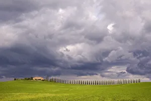 Italy, Tuscany, Val d Orcia. Farmhouse and storm clouds at sunset