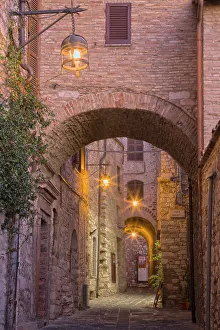Umbria Prints: Italy, Umbria, Assisi. Alleyway with arches and lanterns in the evening