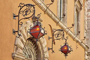 Umbria Prints: Italy, Umbria, Assisi. Wrought iron dragon lights on a wall above an entrance