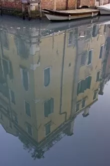 Italy, Venice. Building and boat reflected in still canal