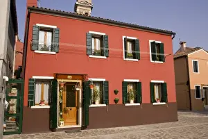Italy, Venice, Burano. A bright orange house with green shutters