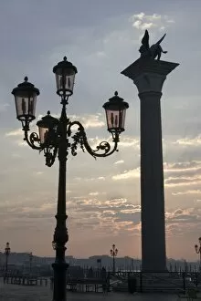 Italy, Venice. Lion of St. Mark atop column and ornate lamp at sunrise