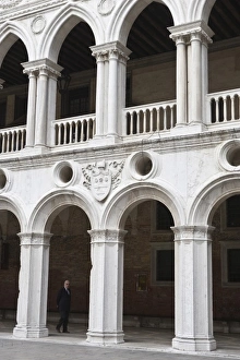 Images Dated 14th May 2006: Italy, Venice. Man walks beneath the arches of the interior of Doges Palace