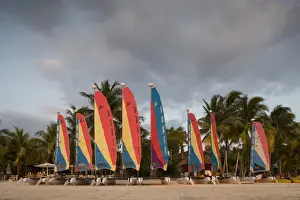 Jamaica Prints: Jamaica, Negril, Setting sun lights row of sailboats at tourist resort along white