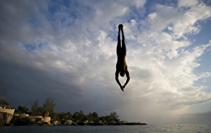 Images Dated 24th April 2007: Jamaica, Negril, Silhouette of young man leaping from from cliff above Pirates Cave