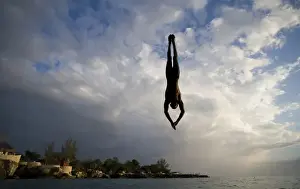 Images Dated 24th April 2007: Jamaica, Negril, Silhouette of young man leaping from from cliff above Pirates Cave