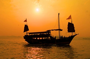 Images Dated 27th March 2012: A junk sails through Aberdeen harbor near Hong Kong at sunset