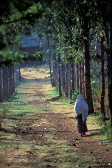 A Konso villager walks down a dirt road that leads to a small Konso village, in the