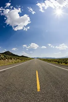 Roadway Prints: A two lane road extending into the distance of southwest Utah leading to the mountainous