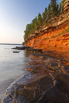 Layered sandstone cliffs and sea caves at sunrise on Devils Island in the Apostle Layered sandstone cliffs and sea caves at sunrise on Devils Island in the Apostle
