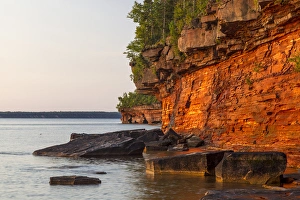 Layered sandstone cliffs and sea caves at sunrise on Devils Island in the Apostle