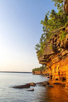 Layered sandstone cliffs and sea caves at sunrise on Devils Island in the Apostle