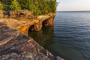 Layered sandstone cliffs and sea caves at sunrise on Devils Island in the Apostle