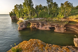 Layered sandstone cliffs and sea caves at sunrise on Devils Island in the Apostle