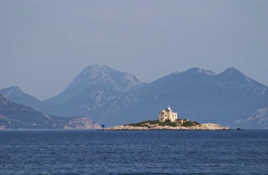 Images Dated 8th July 2006: A lighthouse light house on an island outside the village, blue mountains in the background