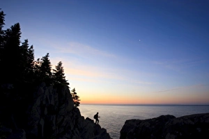A lone hiker at sunrise on the Bold Coast trail in Cutler, Maine. Cutler Coast Public Reserved Land