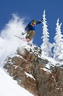 Exciting Prints: Man jumping colorful cliff and skiing in fresh powder at Whitefish Mountain Resort in Montana