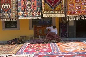 Images Dated 23rd May 2004: Man sewing the sides of a kilim in front of a local carpets shop, Pergamon (Pergamum