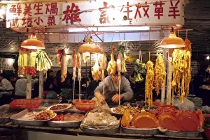 Orient Prints: A man works at a night market selling meat and fish in Hong Kong
