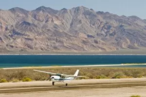 Mexico, Baja California, Bahia de los Angeles. Small aircraft lands with dramatic
