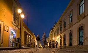 Mexico, Oaxaca, Window shoppers walk along cobblestone pedestrian street past galleries