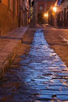 Mexico, San Miguel de Allende. Lanterns reflect on pre-dawn cobblestone street. Credit as
