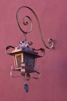 Mexico, San Miguel de Allende. Ornate copper lamp hung from pink-purple wall