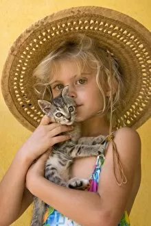 Mexico. Young girl embraces her kitten. (MR)