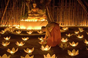 Holding Prints: Monks lighting khom loy candles and lanterns for Loi Krathong festival