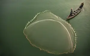 Myanmar, Mandalay, Amarapura. Fisherman casting net on Irrawaddy River. Credit as