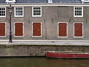 Architecture Collection: Netherlands, Amsterdam. Colorful red doors along the canal with a red boat