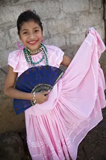 Nicaragua, Granada. Girl with fan in traditional dress after dance in Villa Esperanza barrio