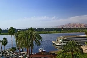 Nile River and docked sightseeing boats, and distant Valley of the Kings, from modern