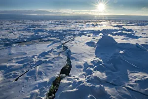 Images Dated 13th December 2021: Norway. Icescape at 84 degrees north, crack in ice with sunburst