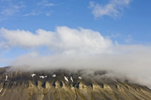 Images Dated 25th July 2008: Norway, Svalbard, Spitsbergen Island, Setting sun lights clouds above eroded cliffs