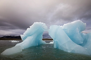 Norway, Svalbard, Spitsbergen Island, Blue arched iceberg floating near face of Sveabreen