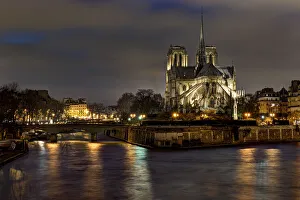 Notre Dame Cathedral and the Seine River shimmer in the Paris, France. night