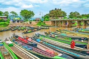 Burma Prints: Nyaungshwe, Myanmar, Asia, Wide angle portrait of Buddhist monk in red robe making his way onto long boat in canal