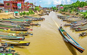 Burma Prints: Nyaungshwe, Myanmar. Wide angle landscape view of long motor boats lining the canal which runs into Inle Lake