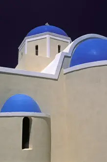 White Church Prints: Oia, Santorini, Greece, Blue domes upon a white church illuminated by the sun in the village of Oia