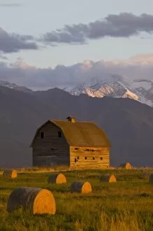 Old barn framed by hay bales and dramatic Mission Mountain Range in Montana
