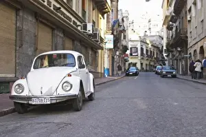 Volkswagen Prints: An old white Volksvagen Beetle probably from the 1960s parked on the street in